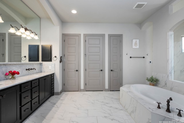 bathroom with vanity and tiled bath