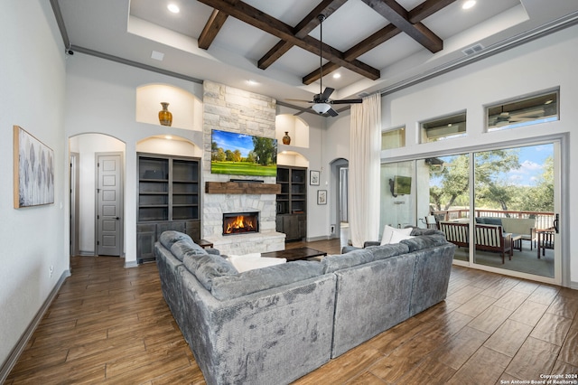 living room featuring a fireplace, ceiling fan, a high ceiling, and dark hardwood / wood-style flooring