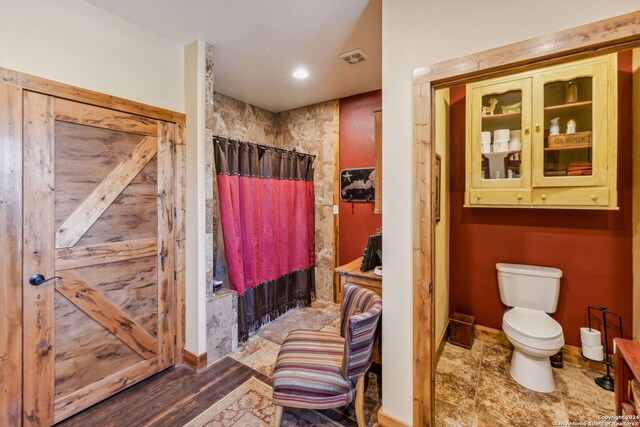 bathroom with toilet, curtained shower, and wood-type flooring