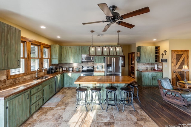 kitchen featuring appliances with stainless steel finishes, butcher block counters, a center island, and backsplash