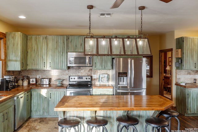 kitchen featuring appliances with stainless steel finishes, ceiling fan, green cabinets, and butcher block counters