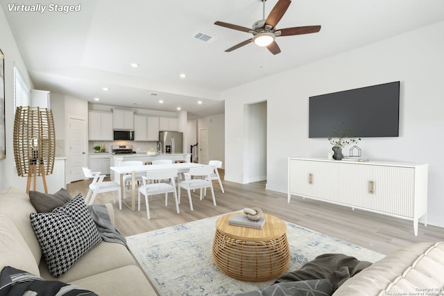 living room with ceiling fan and light wood-type flooring