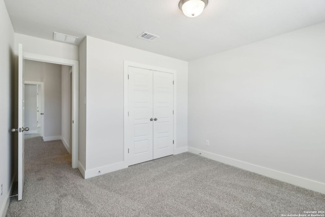 unfurnished bedroom with light carpet and a closet