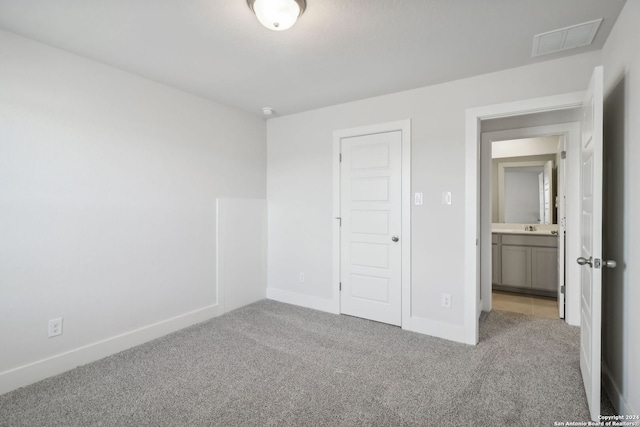 unfurnished bedroom with light carpet, a closet, and sink