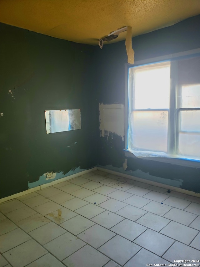 spare room with light tile patterned flooring and a textured ceiling