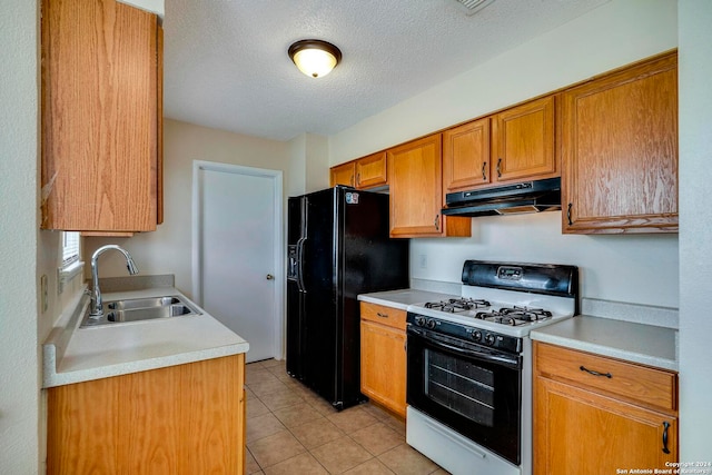 kitchen featuring sink, a textured ceiling, black fridge, gas range gas stove, and light tile patterned floors