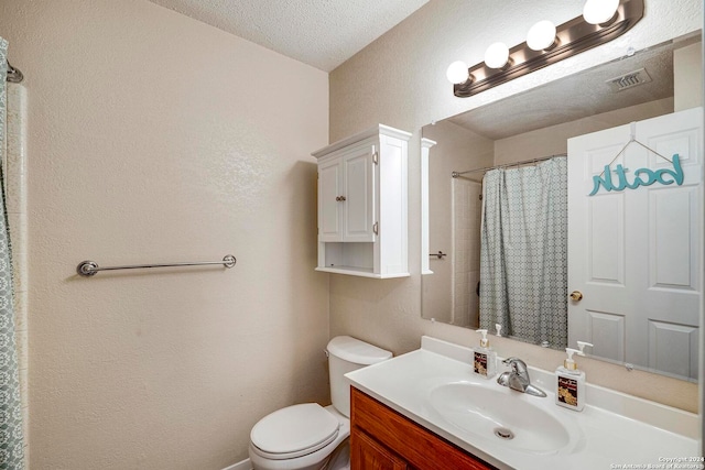 bathroom featuring toilet, a textured ceiling, walk in shower, and vanity