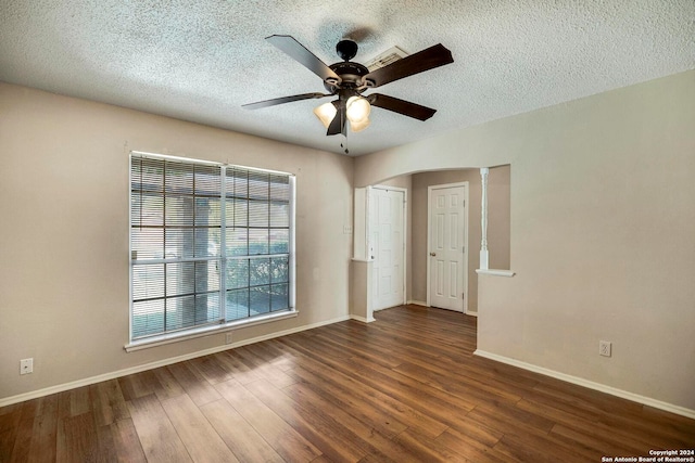 unfurnished room with dark wood-type flooring, ceiling fan, a textured ceiling, and decorative columns