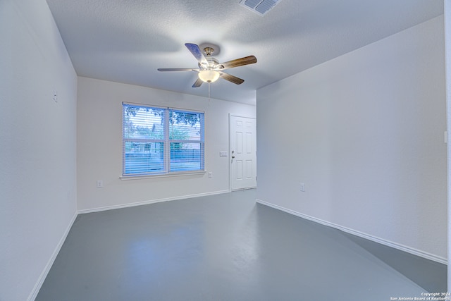 empty room with ceiling fan and a textured ceiling