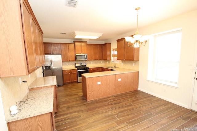 kitchen with hardwood / wood-style floors, sink, hanging light fixtures, and stainless steel appliances