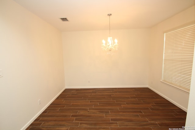 empty room featuring dark hardwood / wood-style floors and an inviting chandelier