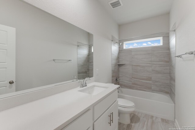 full bathroom featuring tiled shower / bath, vanity, and toilet