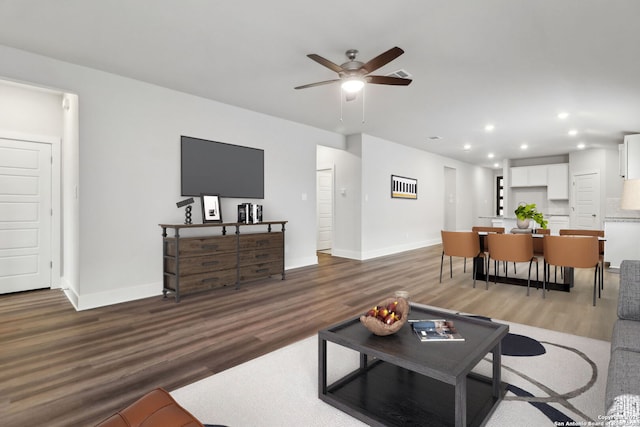 living room with dark wood-type flooring and ceiling fan