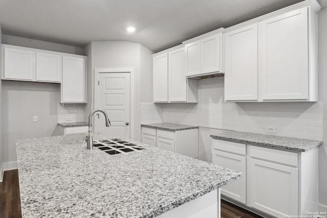 kitchen with white cabinetry, sink, and an island with sink