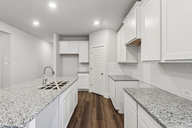 kitchen with dark hardwood / wood-style floors, a kitchen island with sink, sink, and white cabinets