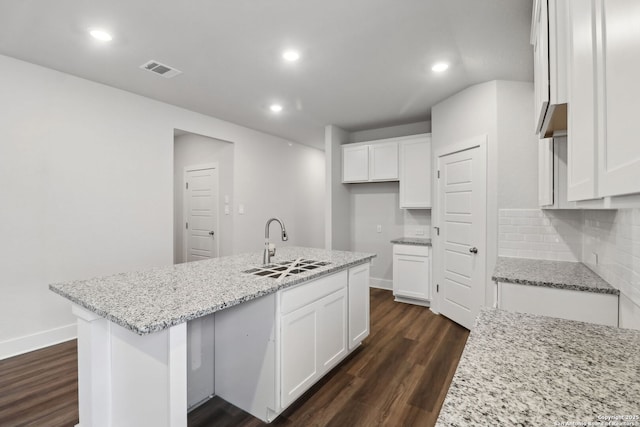 kitchen with white cabinetry, sink, light stone countertops, and a center island with sink