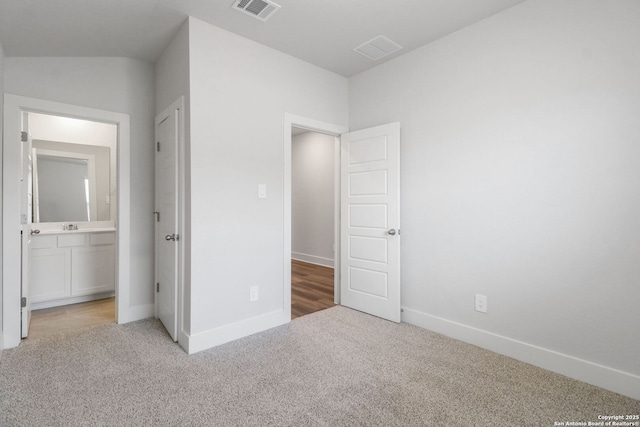 unfurnished bedroom with sink, ensuite bathroom, and carpet