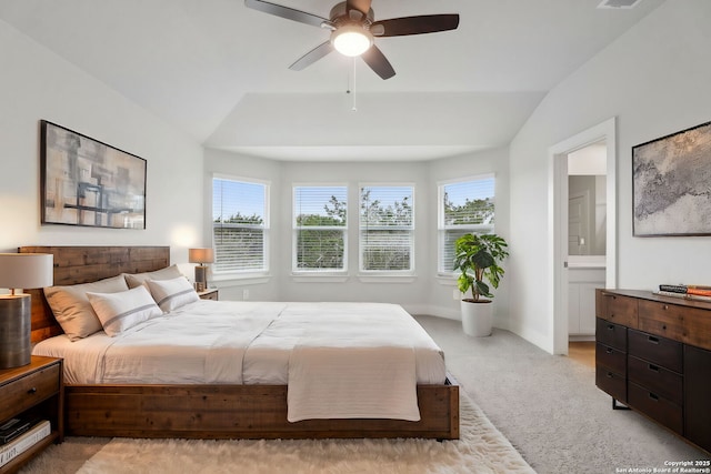 bedroom with ceiling fan, lofted ceiling, light colored carpet, and ensuite bath