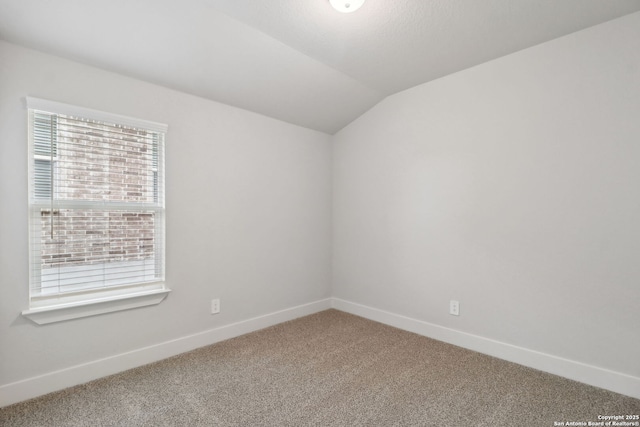 spare room featuring carpet flooring and vaulted ceiling