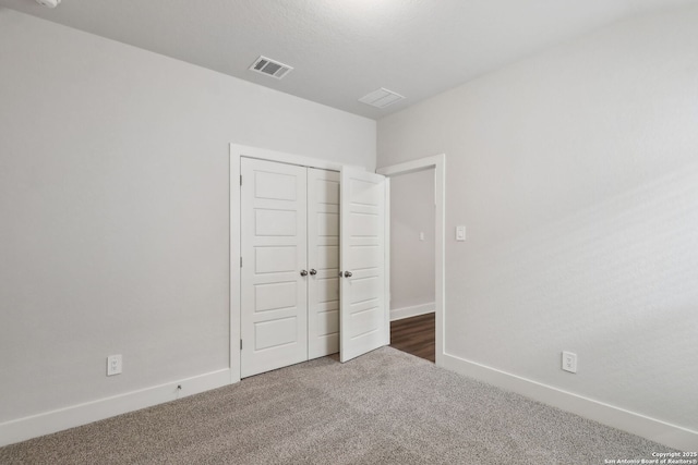 unfurnished bedroom with dark carpet and a closet