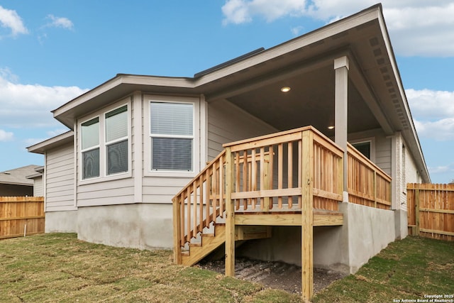 back of property featuring a wooden deck and a lawn