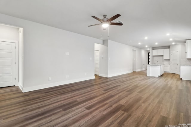 unfurnished living room featuring sink, dark wood-type flooring, and ceiling fan