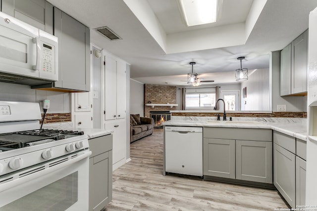 kitchen with white appliances, a fireplace, light hardwood / wood-style flooring, and gray cabinetry