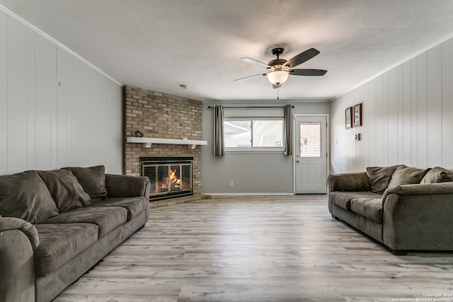 living room featuring ornamental molding, a textured ceiling, a fireplace, and light hardwood / wood-style floors