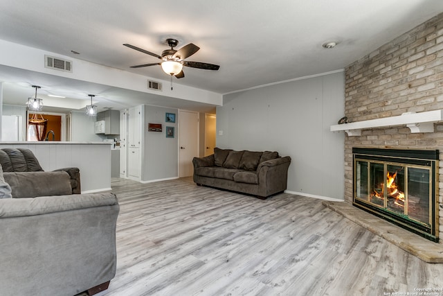 living room featuring light hardwood / wood-style flooring, sink, crown molding, and a brick fireplace