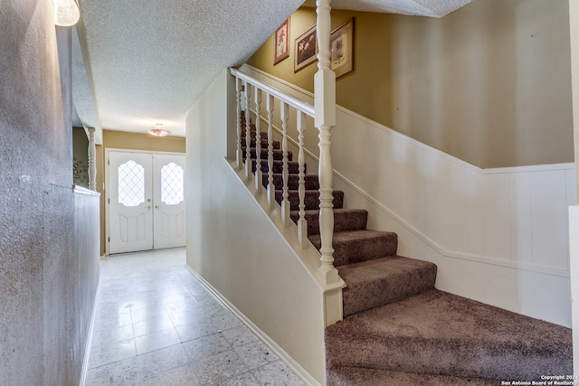 stairway featuring a textured ceiling