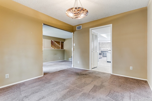 carpeted empty room featuring a textured ceiling