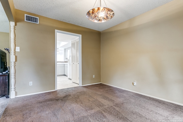 carpeted empty room with a textured ceiling