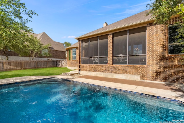 view of swimming pool with a sunroom and a lawn