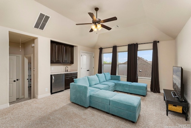 carpeted living room featuring wet bar, vaulted ceiling, and ceiling fan