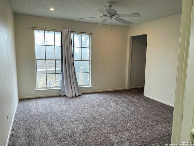 carpeted spare room featuring a textured ceiling and ceiling fan