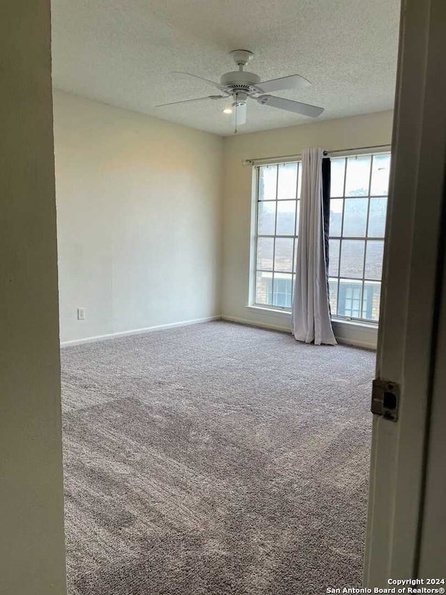 unfurnished room featuring carpet floors, a textured ceiling, and ceiling fan