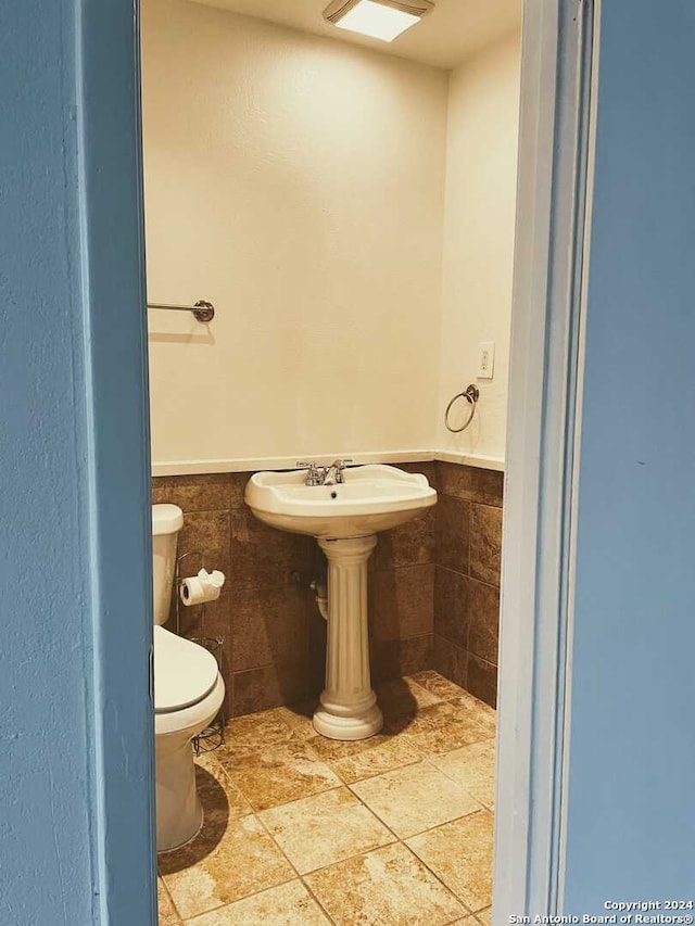 bathroom with toilet and tile walls