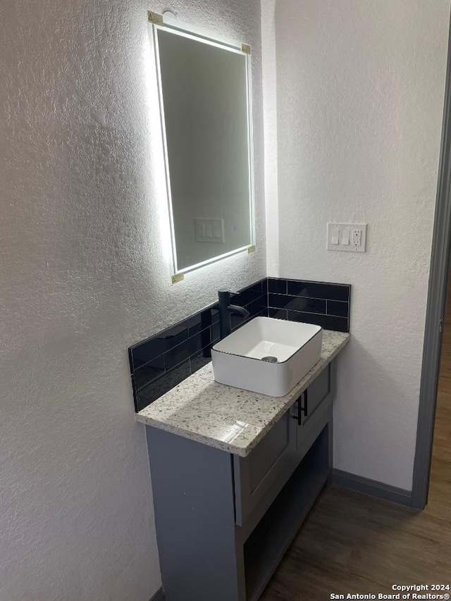 bathroom featuring vanity, hardwood / wood-style floors, and backsplash