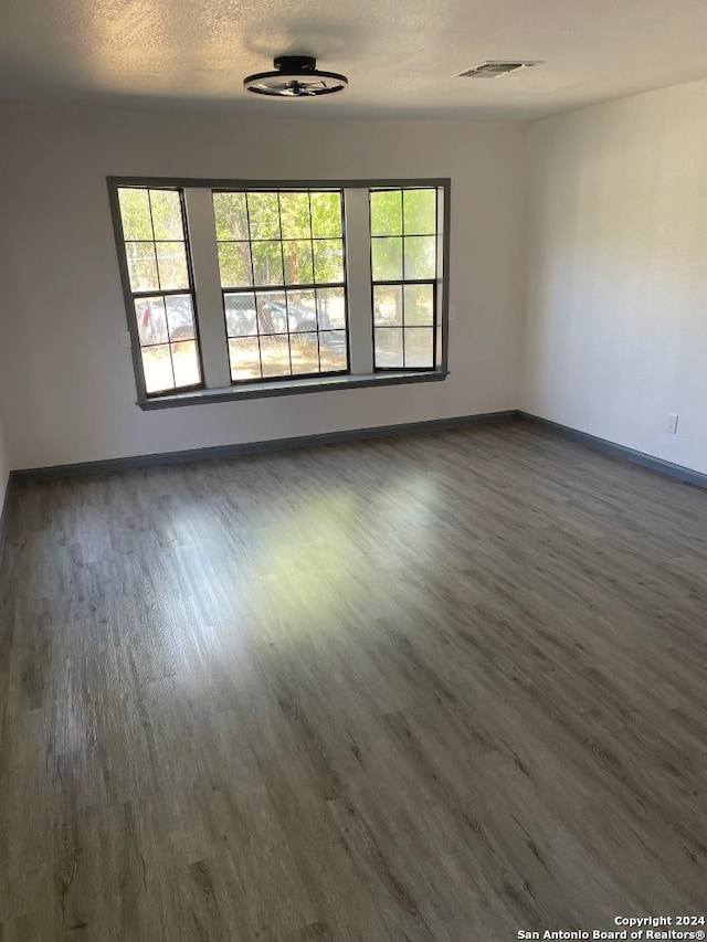 spare room with a textured ceiling and dark wood-type flooring