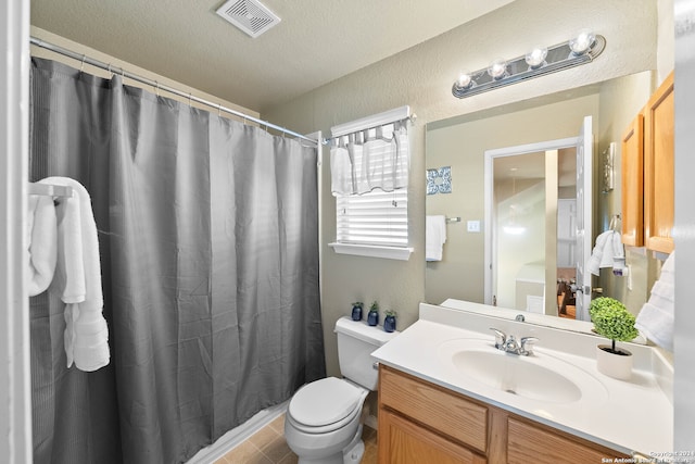 bathroom featuring vanity, a textured ceiling, toilet, and walk in shower