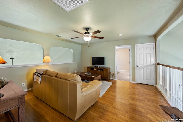 living room featuring ceiling fan, a textured ceiling, and light hardwood / wood-style flooring