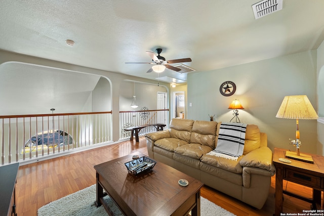 living room featuring ceiling fan, a textured ceiling, and hardwood / wood-style floors