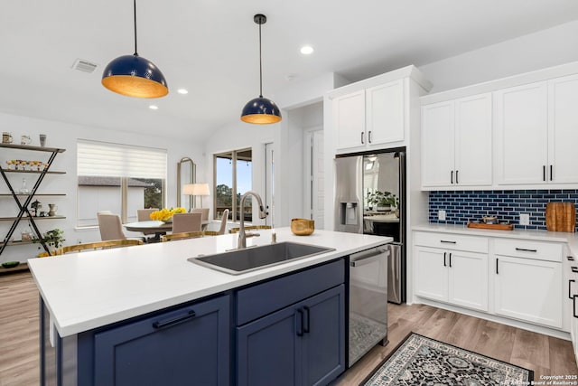 kitchen with sink, white cabinetry, stainless steel appliances, tasteful backsplash, and decorative light fixtures