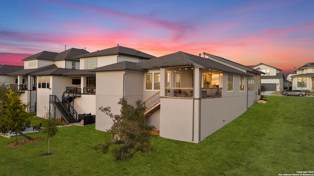 back house at dusk with a lawn