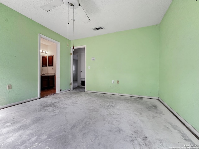 unfurnished bedroom featuring ceiling fan, ensuite bathroom, a textured ceiling, and concrete flooring