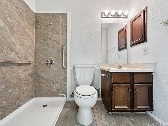 bathroom with vanity, tiled shower, and toilet