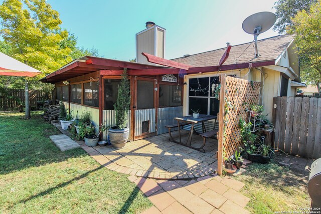 back of property featuring a patio area, a lawn, and a sunroom