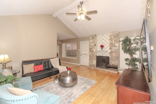 living room with vaulted ceiling with beams, a stone fireplace, hardwood / wood-style flooring, and ceiling fan with notable chandelier