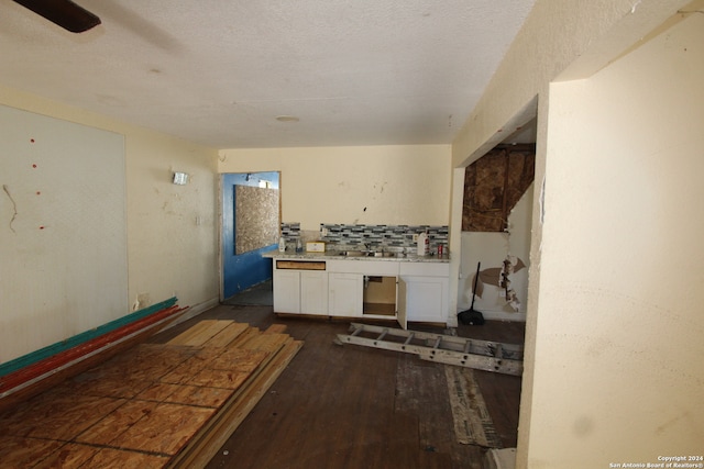 kitchen featuring sink, a textured ceiling, dark hardwood / wood-style flooring, white cabinets, and decorative backsplash