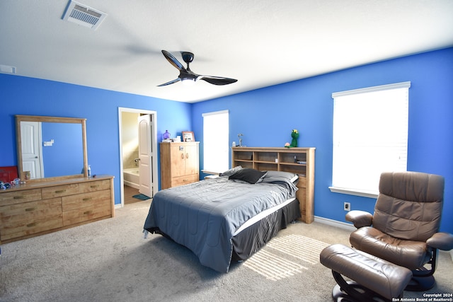 carpeted bedroom with multiple windows, connected bathroom, and ceiling fan